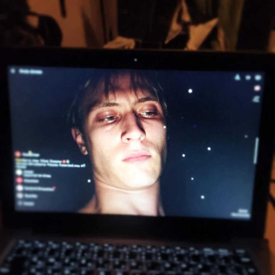 Tired reflection in dark laptop during late-night scroll