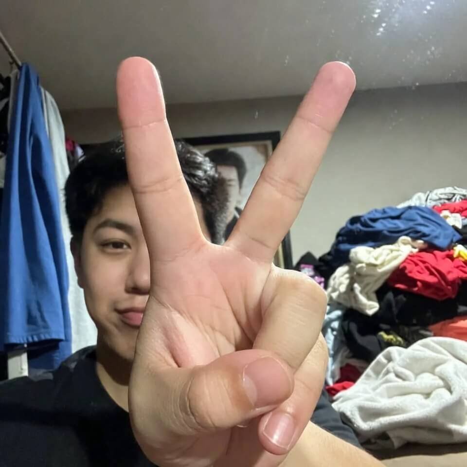 Awkward peace sign in messy mirror selfie with laundry pile