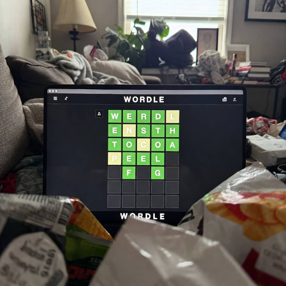 Half-solved Wordle on couch with snack mess