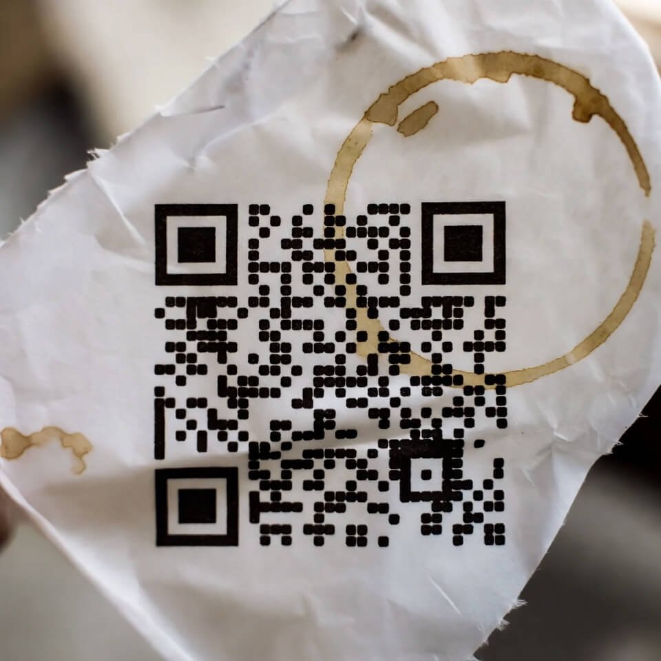 Wrinkled Starbucks napkin with failed hand-drawn QR and coffee stain